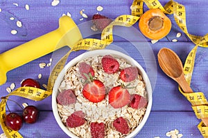 Oat flakes or oatmeal with fruits, dumbbells and centimeter. Slimming, sporty lifestyle and healthy nutrition