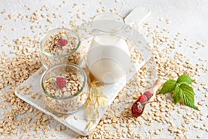 Oat flakes, out milk and rasberry on a table. Plant-based healthy and vegetarian eating and drink. Selective focus, close up