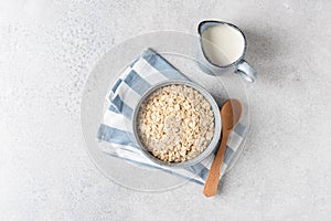 Oat flakes, rolled oats in bowl and jug of milk