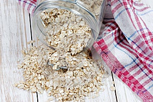 Oat flakes spilling from the glass jar on wooden table