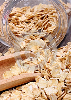 Oat flakes spilling out of jar on wooden background