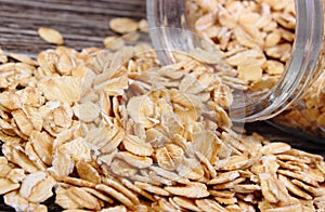 Oat flakes spilling out of jar on wooden background