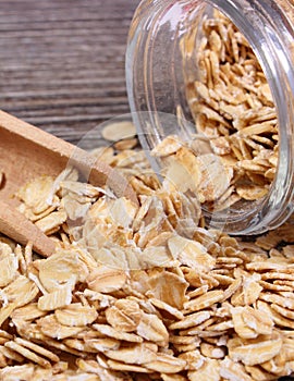 Oat flakes spilling out of jar on wooden background