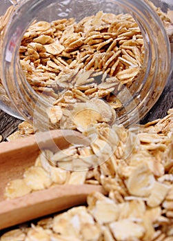 Oat flakes spilling out of jar on wooden background