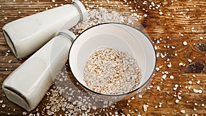 Oat flakes in white bowl and bottles of fresh milk