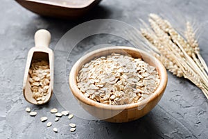 Oat flakes in wooden bowl and golden wheat ears