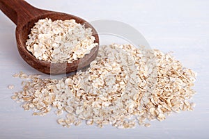 Oat flakes in wooden spoon on white background