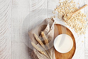 Oat milk in a glass, flakes of baked cereals. Milk substitute, milk for vegetarians. Flatlay. Copy space.