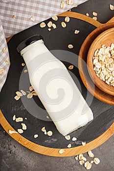 Oat milk in the glass with jug of milk and oat on a wooden background