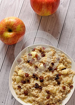 Oatmeal with apple and raisins against the background of the old tree. Muesli with an apple and raisins