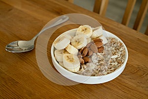 Oatmeal with banana, honey and almonda for breakfast on a table