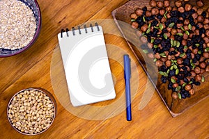 Oatmeal and blank page notepad on wooden table. Healthy breakfast recipe. Porridge musli and notebook top view photo