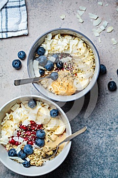 Oatmeal bowl with banana, berries, hemp seeds and coconut slices, top view. Healthy vegan breakfast concept