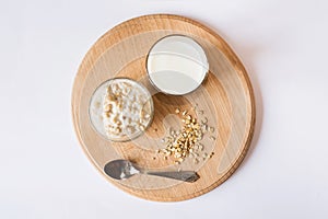 Oatmeal in a bowl with a glass of milk on a wooden board on a white background. A healthy and nutritious morning breakfast