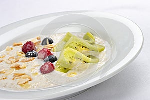 Oatmeal breakfast with berries and kiwi on white background