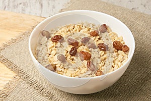 Oatmeal breakfast bowl. Organic healthy food with candied fruit, raisins, nuts