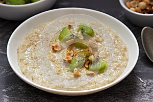 Oatmeal breakfast with butter, kiwi, hazelnuts and cinnamon