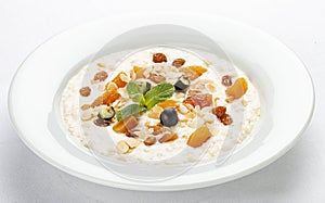 Oatmeal breakfast with raisins, dried apricots and peanuts on white background