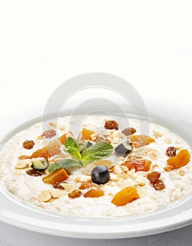 Oatmeal breakfast with raisins, dried apricots and peanuts on white background