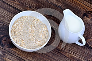 Oatmeal in a ceramic bowl and pitcher with milk on table