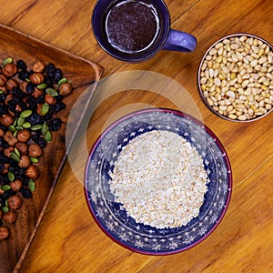 Oatmeal cereal with nut and coffee cup. Healthy breakfast square photo. Morning meal on wooden table top view