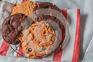 Oatmeal cookie milk cookie and chocolate chip nut cookie on grate metal red and white napkin black background. photo