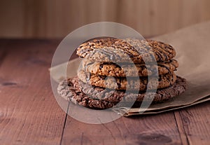 Oatmeal cookies with chocolate on a brown paper on a wooden table. Cookies with chocolate lie on a wooden table