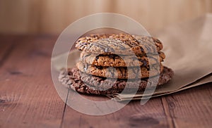 Oatmeal cookies with chocolate on a brown paper on a wooden table. Cookies with chocolate lie on a wooden table