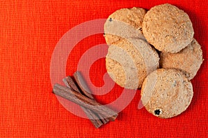 Oatmeal cookies and cinnamon sticks on orange linen background