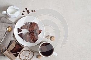 Oatmeal cookies with cocoa and chocolate on a white plate and in a cardboard box, cup of coffee and a milk jug