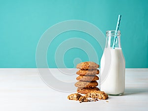 Oatmeal cookies with flax seeds and milk in bottle, healthy snack. Light background, bright blue wall