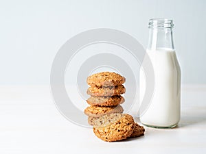 Oatmeal cookies with flax seeds and milk in bottle, healthy snack. Light background, grey light wall