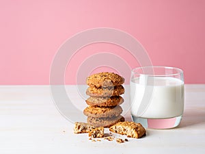 Oatmeal cookies with flax seeds and milk in a glass, healthy snack. Light background, bright pink wall