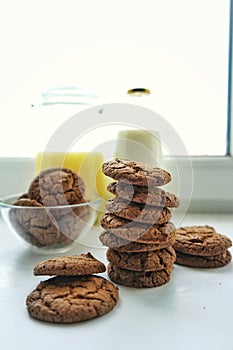 Oatmeal cookies on a light window background, with milk and pineapple orange juice