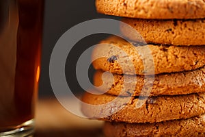 Oatmeal cookies with pieces of chocolate and a mug of coffee on a bamboo stand. Macro