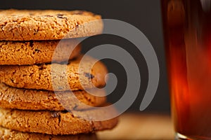 Oatmeal cookies with pieces of chocolate and a mug of coffee on a bamboo stand. Macro