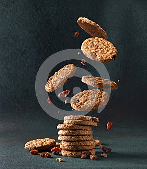 Oatmeal cookies with raisin falling into a stack. Levitating oatmeal cookies on a dark background