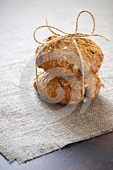 Oatmeal cookies with raisins and fillers tied with a rope with a bow on the rough gray tablecloth and dark tabletop