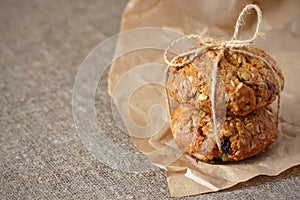 Oatmeal cookies two with raisins and fillers tied with a rope with a bow on kraft wrapping paper rough and gray tablecloth