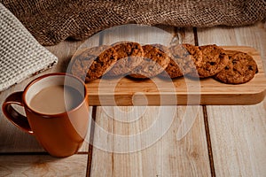 Oatmeal cookies on a wooden plate with a cup of coffee with milk. The concept of natural and delicious food.