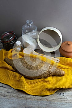 Oatmeal diet bread on a yellow towel in the background is satiated for flour, a jar of flour, spices and a spoon