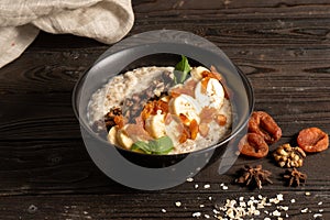 Oatmeal with dried apricots, banana and walnuts, cooked in milk and decorated with mint chanterelles. Healthy diet vegetarian brea