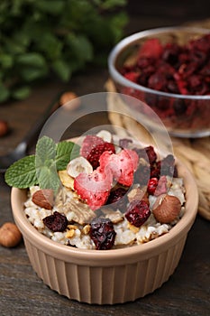 Oatmeal with freeze dried fruits, nuts and mint on wooden table