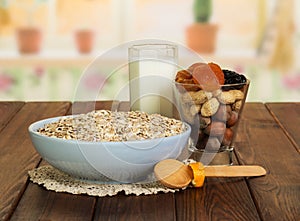 Oatmeal, milk, nuts, dried fruit on background of kitchen.