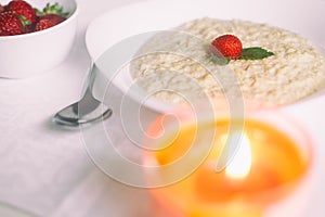 Oatmeal with milk. Porridge with milk. Cereals, delicious Breakfast, diet Breakfast. Candle. Strawberries, oatmeal and