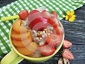 Oatmeal, nuts, strawberry, apricot,organic breakfast snack delicious heart on a black wooden background