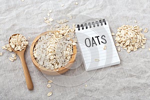 Oatmeal, oat cereal in wood bowl with oats word on notebook