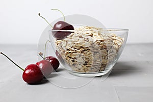oatmeal oatmeal porridge in a glass plate bowl bowl with cherry berries on a gray background with space for text and copyspace.