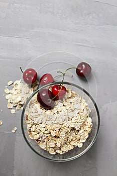 oatmeal oatmeal porridge in a glass plate bowl bowl with cherry berries on a gray background with space for text and copyspace.