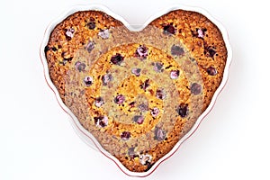 Oatmeal pie with cherry in the ceramic form in the shape of a heart on a white background